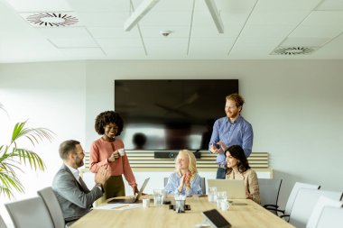 Bir grup profesyonel dizüstü bilgisayarın etrafında toplanarak parlak bir ofis ortamında fikir alışverişinde bulundu..