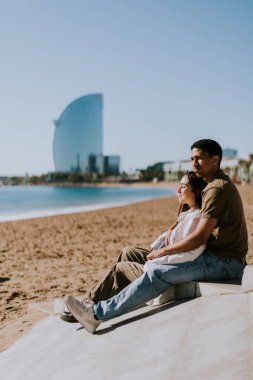 Arkaplanda ikonik otel olan Barcelonas kumlu sahillerinde bir çift rahatlıyor.