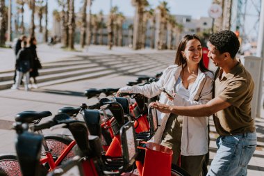 Genç çift, Barcelona 'daki kiralık bir istasyondan bisiklet seçerek keyifli bir gün geçiriyor..
