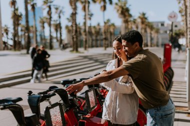 Genç çift, Barcelona 'daki kiralık bir istasyondan bisiklet seçerek keyifli bir gün geçiriyor..