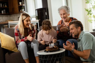 Mutlu bir büyükanneye doğum günü pastası sunmak için kanepenin üzerinde toplanan çok nesilli bir ailenin anılarını canlandırması iç açıcı bir sahne.