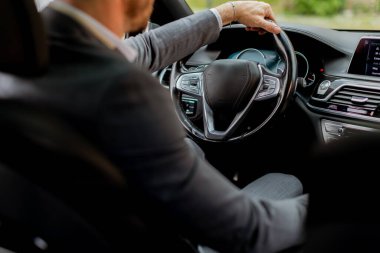 Neşeli sürücü direksiyonu tutarken gülümser, iyi donanımlı bir araçla yolda ilerler.