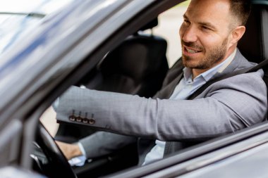 Neşeli sürücü direksiyonu tutarken gülümser, iyi donanımlı bir araçla yolda ilerler.