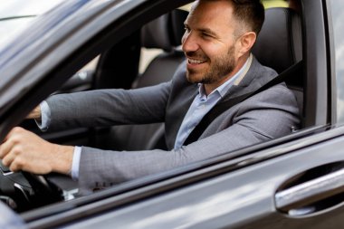 Neşeli sürücü direksiyonu tutarken gülümser, iyi donanımlı bir araçla yolda ilerler.