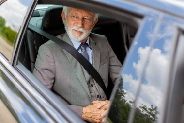 Onurlu, sakallı yaşlı bir adam şoför koltuğundan sıcak bir şekilde gülümsüyor, seyahat etmeye hazır.