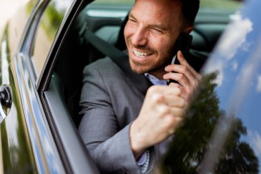 Adam araba sürerken neşeli bir şekilde kıkırdıyor, cep telefonunda neşeli bir sohbetin tadını çıkarıyor.