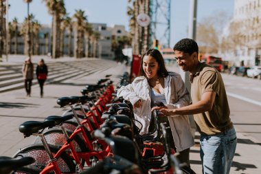 Genç çift, Barcelona 'daki kiralık bir istasyondan bisiklet seçerek keyifli bir gün geçiriyor..