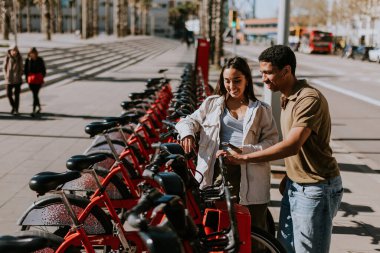Genç çift, Barcelona 'daki kiralık bir istasyondan bisiklet seçerek keyifli bir gün geçiriyor..
