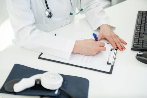 Doctor in a white coat documents medical details while seated at a desk — Stock Image Doctor White Coat Documents Medical Details While Seated Desk Stock Picture