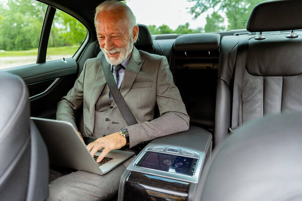 Senior man concentrates on his laptop while sitting in the parked cars backseat — Stock Image Senior Man Concentrates His Laptop While Sitting Parked Cars Backseat Stock Picture