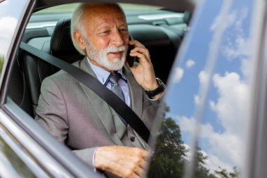 Rahat bir araba yolculuğunda, tatlı yaşlı adam cep telefonuyla sohbet eder. Cazibesi ve kendine güveni vardır.