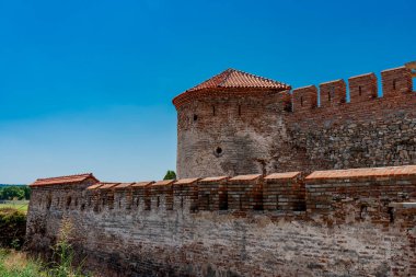 Ancient walls and red-tiled roof of Fetislam Fortress stand proudly against a vibrant summer sky. clipart