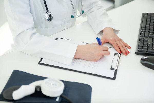 Doctor in a white coat documents medical details while seated at a desk — Stock Image Doctor White Coat Documents Medical Details While Seated Desk Royalty Free Stock Photos