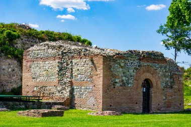 Ancient Roman ruins of Felix Romuliana stand majestically near Gamzigrad, Serbia, surrounded by lush greenery under a clear blue sky clipart