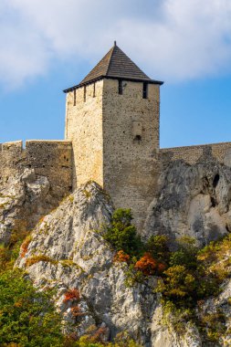 Sersemletici ortaçağ kalesi kayalık uçurumlara tünemiş berrak mavi gökyüzü ve canlı sonbahar yapraklarıyla Tuna nehrinin dingin zeminini güçlendiriyor.