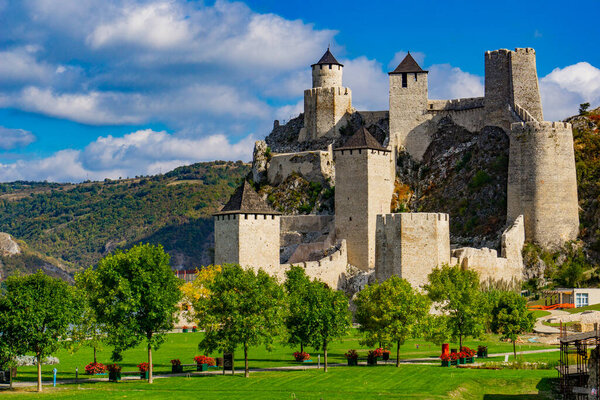 Stunning view of Golubac Fortress, a medieval stronghold perched on a rocky cliff overlooking the Danube River in Serbia. The fortress, a symbol of Serbias rich history, is surrounded by lush green hills and a vibrant blue sk — Stock Image Stunning View Golubac Fortress Medieval Stronghold Perched Rocky Cliff Overlooking Stock Photo