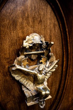 Entrika ile tasarlanmış kapı tokmağı, uzanmış kanatları olan zarif bir meleği gösteriyor. Ziyaretçileri tarihin dik kalmış Paris zarafetine davet ediyor.