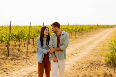 Neşeli çift, canlı üzüm bağları ve altın toprakla çerçevelenmiş, sıcak güneşin altında gülüşlerini ve kucaklaşmalarını paylaşıyor.