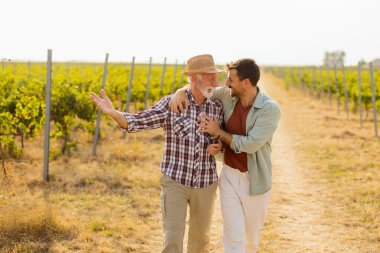Güneşli bir üzüm bağında tozlu bir yolda yürürken, iki adam açık yürekli bir sohbete girişir, dostlukları, yayılan üzümlerin arka planına karşı aşikardır.