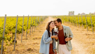 Batan güneşin sıcacık parıltıları altında, birkaç çift, üzüm bağlarında şarap yudumlarken kahkahalarını paylaşıyor, üzüm bağlarının arasında sevgi dolu anılar yaratıyor.