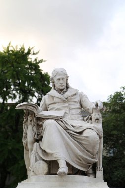 Wilhelm von Humboldt 'un heykeli Berlin, Almanya' daki adaşı olan üniversitenin önünde görkemli bir şekilde duruyor. Yeşillik içinde, eğitim ve düşünce üzerindeki derin etkisini simgeliyor.