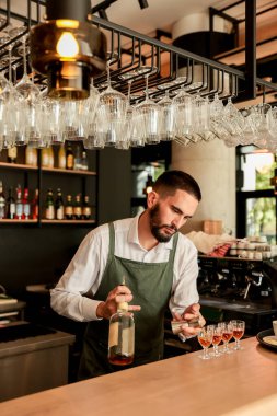 Barmen zarif bardaklara ustalıkla canlı kokteyller döker, uzmanlığını bir bardaki çeşitli ruhlarla dolu raflara karşı sergiler.