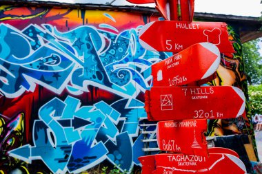 Copenhagen, Denmark - June 14, 2018: Colorful graffiti enlivening a wall in Freetown Christiania features various artistic styles, complemented by quirky directional signs guiding visitors to distant skateparks clipart