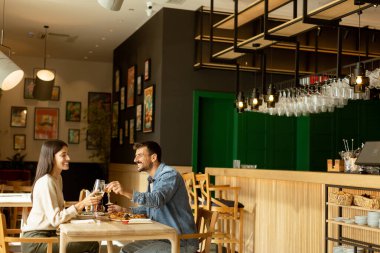 Parlak bir restoranda leziz mutfakların tadını çıkarırken neşeli bir sohbete girişen bir çift, keyifli bir yemek eşliğinde kahkaha ve iletişim anlarını paylaşıyor..