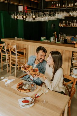 Birkaç arkadaş, üzerinde taze malzemeler olan ve yanında bir bardak şarapla birlikte mükemmel pişmiş pizzanın tadını çıkaran bir kır masasının üzerinde bir anı paylaşıyor..