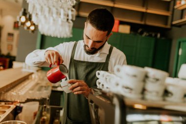 In a warm and inviting cafe, a dedicated barista expertly pours milk into a coffee  cup, creating a delightful experience for patrons. clipart