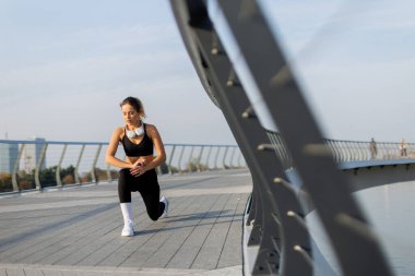 Sabah ışığında, kendini adamış genç bir kadın zarif bir şehir köprüsünde hareketli bir hareket sergiliyor, azim ve zarafetle yeni bir günün tazeliğini kucaklıyor..