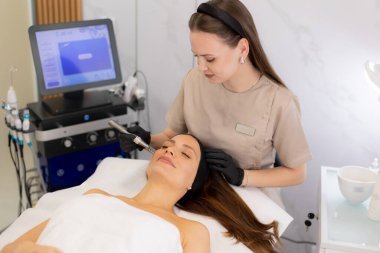 Yetenekli bir pratisyen, müşterinin derisini canlandırmak için mikro terapi aleti kullanır. Huzurlu güzellik kliniği atmosferi dönüştürücü tedavi deneyimini tamamlıyor.