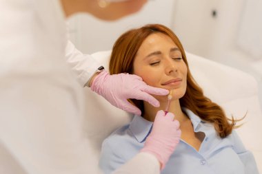 Yetenekli bir pratisyen, sakin bir klinik ortamında gevşemiş bir müşteriye dudak dolgusu uygular..