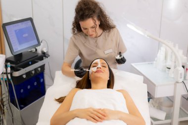Rahatlatıcı bir spa ortamında, hasta, profesyonel estetik uzmanı olarak canlandırıcı bir yüz ifadesinden zevk alır. Besleyici bir maske takar, rahatlamayı ve gençleştirmeyi teşvik eder..
