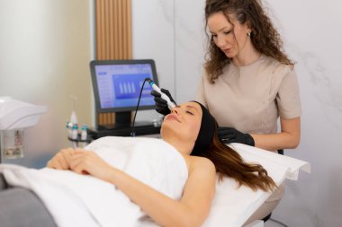 Becerikli bir pratisyen, sağlıklı bir spanın iyileştirici atmosferinin keyfini çıkaran rahat bir müşteri için gözenek temizleme ve sıvı alma üzerine odaklanarak canlandırıcı bir cilt bakımı uygular..