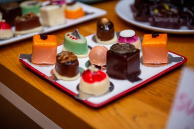 A colorful array of artisan chocolates is elegantly presented on a stylish plate during a joyful confectionery event. Each piece is crafted with unique flavors and artistic designs. clipart