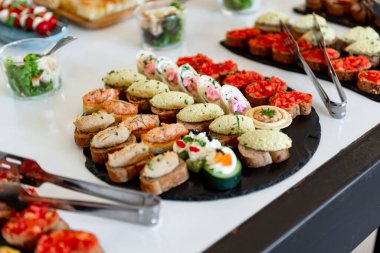 Renkli kanepeler zarif bir şekilde sergilenir. Konukları coşkulu bir kutlamaya davet eder, tüm damak tadlarına lezzet ve dokuların bir karışımını sunarlar..