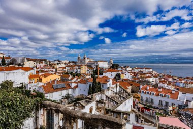 Lizbon 'un renkli çatıları dramatik bir gökyüzü altında Tagus Nehri' nin sakin sularının yanında tarihi mimarinin bir karışımını sergiliyor.