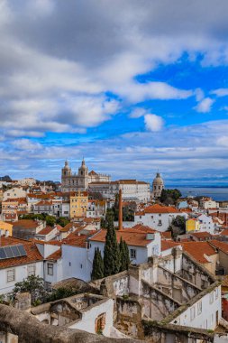 Lizbon 'un renkli çatıları dramatik bir gökyüzü altında Tagus Nehri' nin sakin sularının yanında tarihi mimarinin bir karışımını sergiliyor.