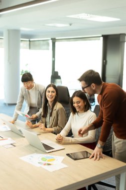 Çeşitli profesyonellerden oluşan bir grup dinamik bir beyin fırtınası yapıyor. Fikir alışverişinde bulunurlar, dizüstü bilgisayarlarda işbirliği yaparlar ve belgeleri açık ve parlak bir çalışma alanında paylaşırlar..