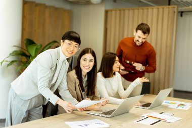 Çeşitli profesyonellerden oluşan bir grup dinamik bir beyin fırtınası yapıyor. Fikir alışverişinde bulunurlar, dizüstü bilgisayarlarda işbirliği yaparlar ve belgeleri açık ve parlak bir çalışma alanında paylaşırlar..
