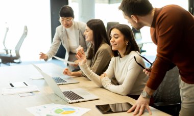 Çeşitli profesyonellerden oluşan bir grup dinamik bir beyin fırtınası yapıyor. Fikir alışverişinde bulunurlar, dizüstü bilgisayarlarda işbirliği yaparlar ve belgeleri açık ve parlak bir çalışma alanında paylaşırlar..