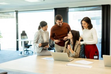Çeşitli profesyonellerden oluşan bir grup dinamik bir beyin fırtınası yapıyor. Fikir alışverişinde bulunurlar, dizüstü bilgisayarlarda işbirliği yaparlar ve belgeleri açık ve parlak bir çalışma alanında paylaşırlar..