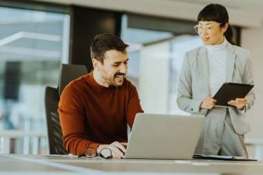 İki profesyonel, biri laptoplarındaki verileri incelerken diğeri ise tabletle birlikte parlak bir ofisteki işbirliği çabalarını ilerletmeye çalışırken, dinamik bir tartışmaya girişiyor..