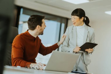 İki profesyonel, biri laptoplarındaki verileri incelerken diğeri ise tabletle birlikte parlak bir ofisteki işbirliği çabalarını ilerletmeye çalışırken, dinamik bir tartışmaya girişiyor..