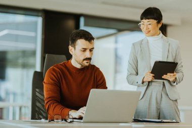 İki profesyonel, biri laptoplarındaki verileri incelerken diğeri ise tabletle birlikte parlak bir ofisteki işbirliği çabalarını ilerletmeye çalışırken, dinamik bir tartışmaya girişiyor..