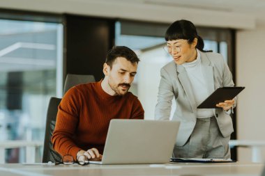 İki profesyonel, biri laptoplarındaki verileri incelerken diğeri ise tabletle birlikte parlak bir ofisteki işbirliği çabalarını ilerletmeye çalışırken, dinamik bir tartışmaya girişiyor..