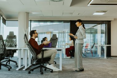 İki profesyonel, çağdaş bir ofiste otururken canlı bir tartışmaya girişirler. Güneş ışığı büyük pencerelerden süzülür, odaklanmış etkileşimlerini aydınlatır.