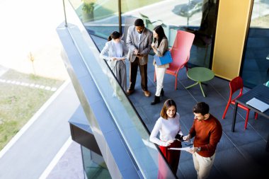 Bir grup profesyonel, çağdaş bir ofis balkonunun havadar alanının keyfini çıkarırken bir projede işbirliği yapıyor. Güneş ışığı geniş pencerelerden süzülerek canlı tartışmalarını geliştirir..