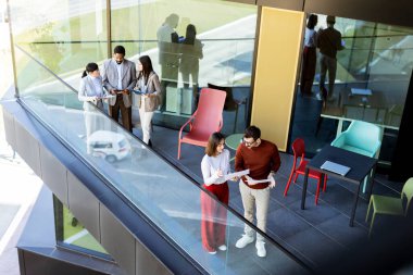 Bir grup profesyonel, çağdaş bir ofis balkonunun havadar alanının keyfini çıkarırken bir projede işbirliği yapıyor. Güneş ışığı geniş pencerelerden süzülerek canlı tartışmalarını geliştirir..